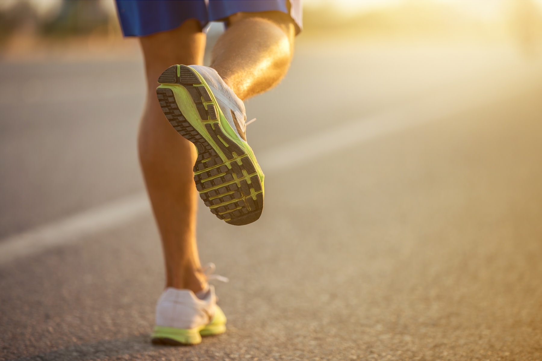 Close-up photo of a man's shoes as he runs with plantar fasciitis outside at dusk.