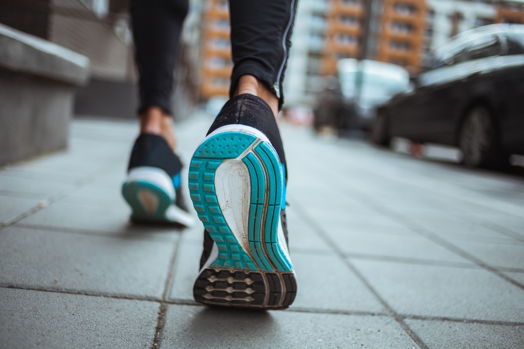 A close-up behind view of a woman's shoes as she runs with plantar fasciitis.