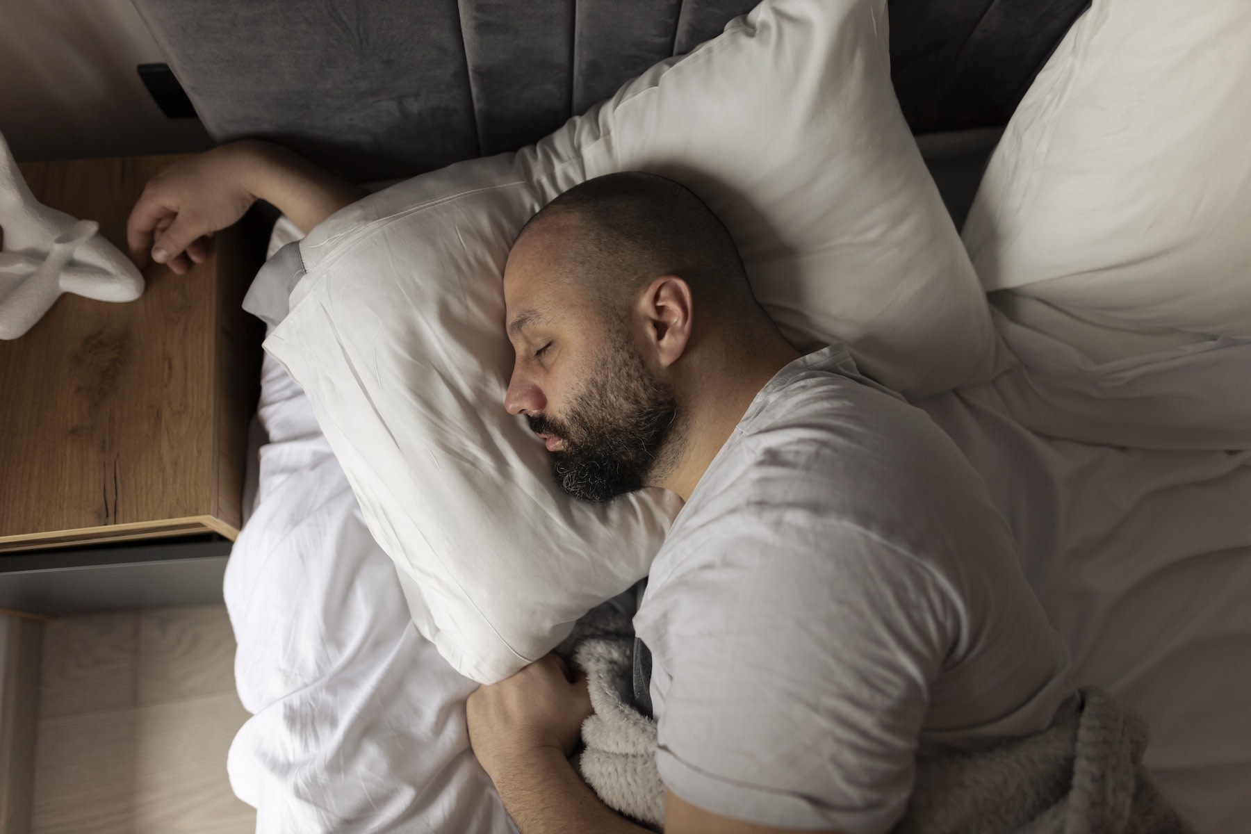 A man sleeping on his side peacefully in bed after going to sleep early.