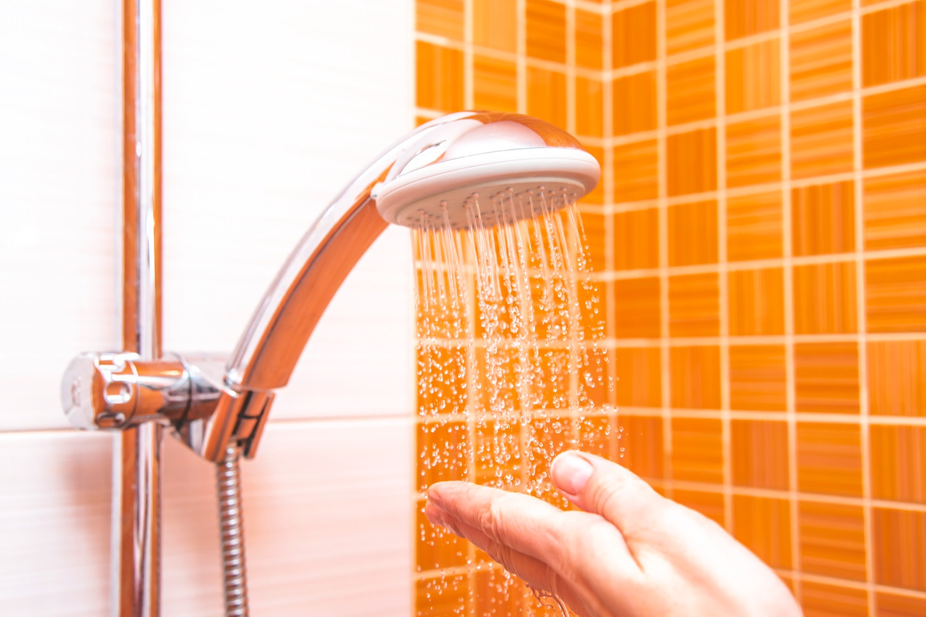 A hand checking the temperature of a shower after a workout.