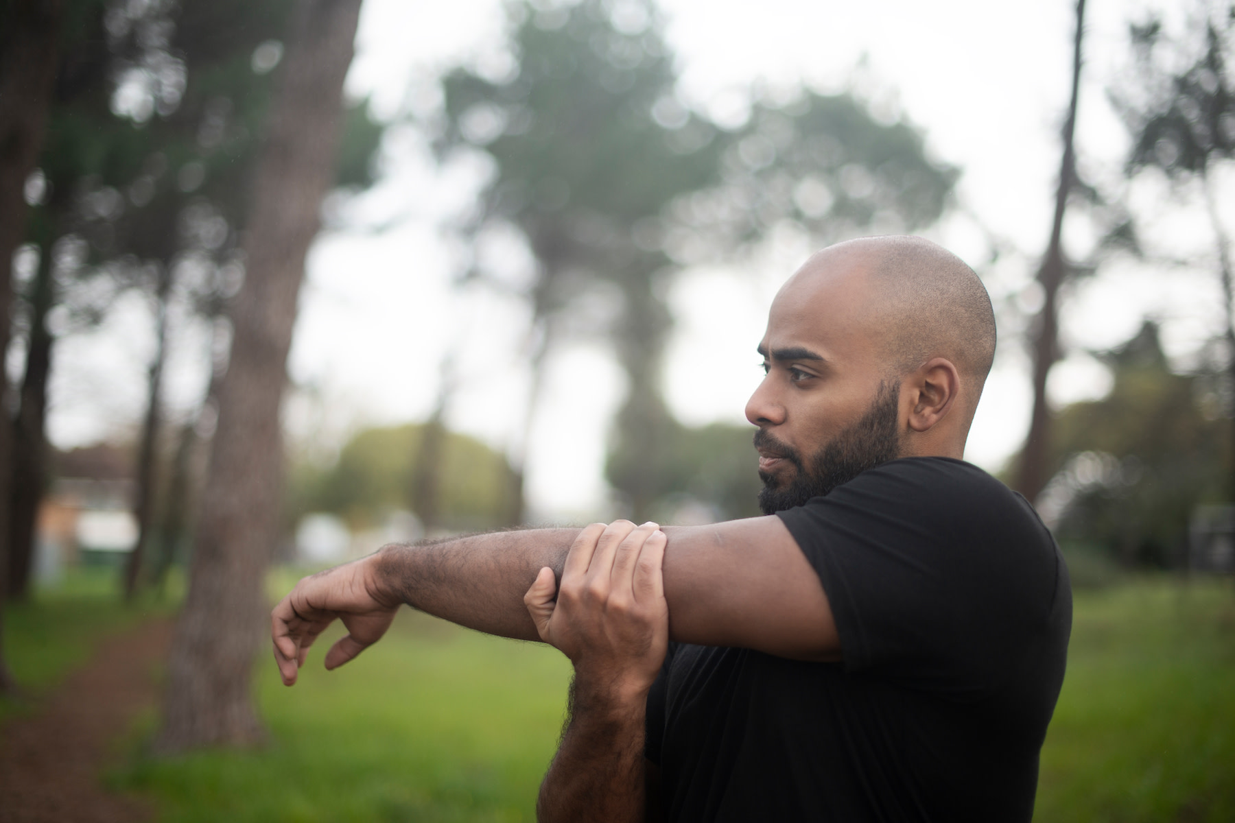 Man does a cross-body shoulder stretch, a shoulder mobility exercise