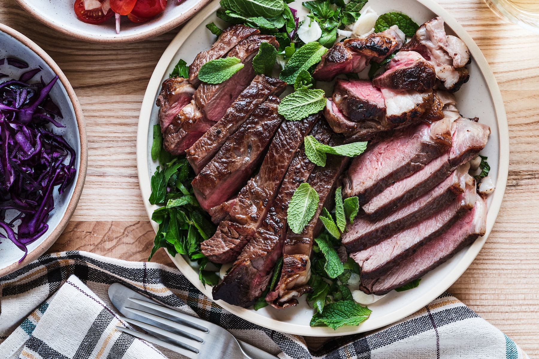 A plate of cooked steak cut up and arranged on a plate with greens. Learn how much protein is too much in this article.