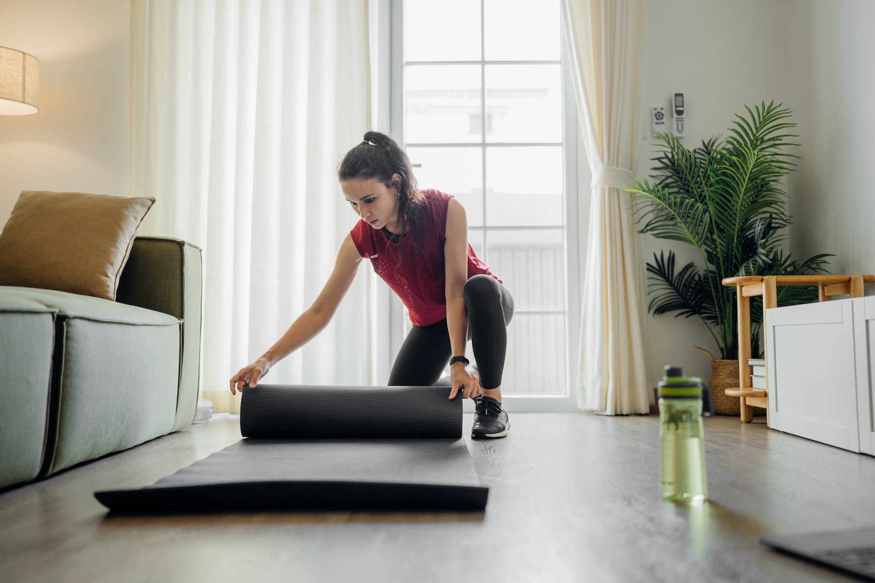 Woman unrolls a yoga mat to practice yoga for cyclists