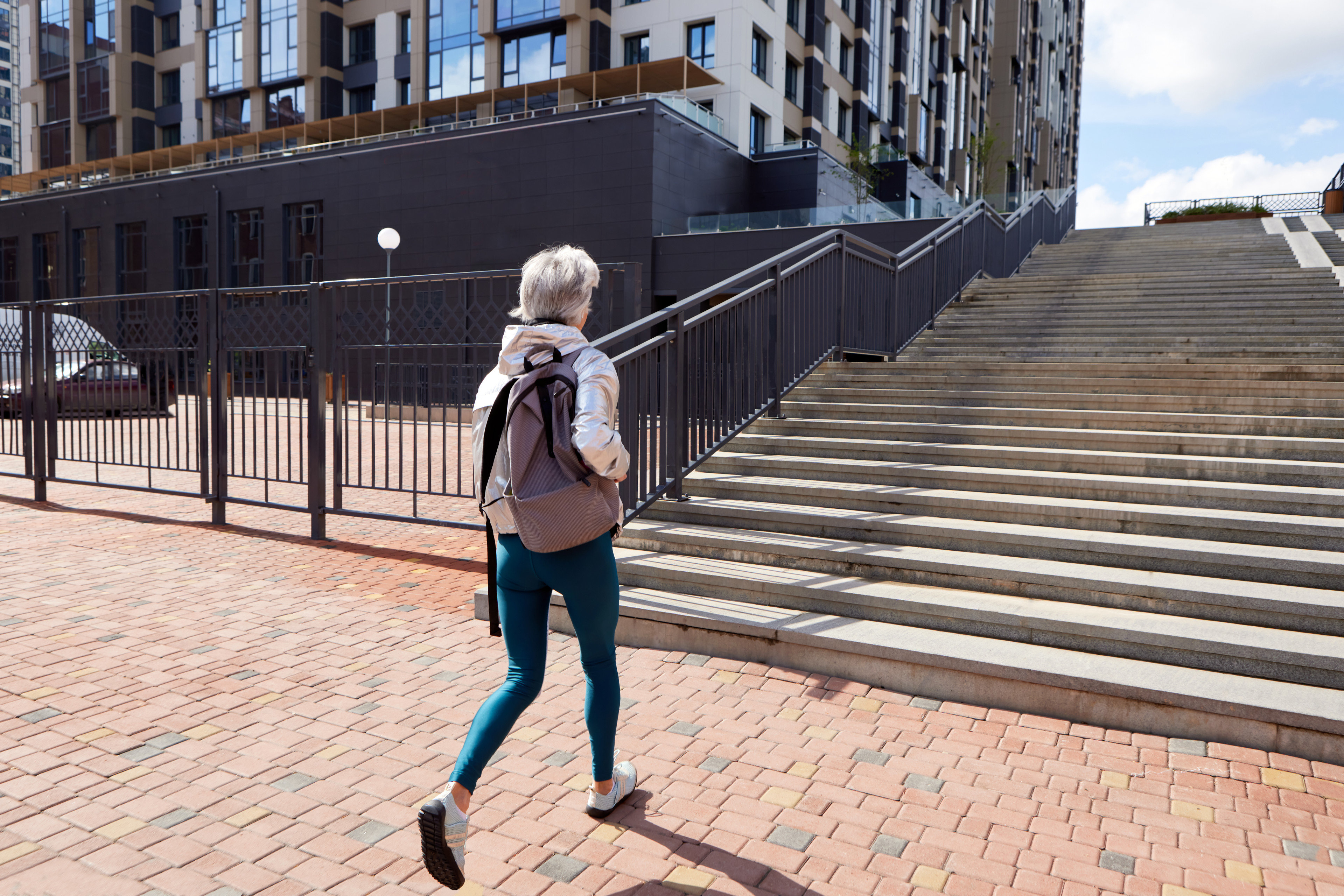 Woman wearing a backpack walks towards steps outside