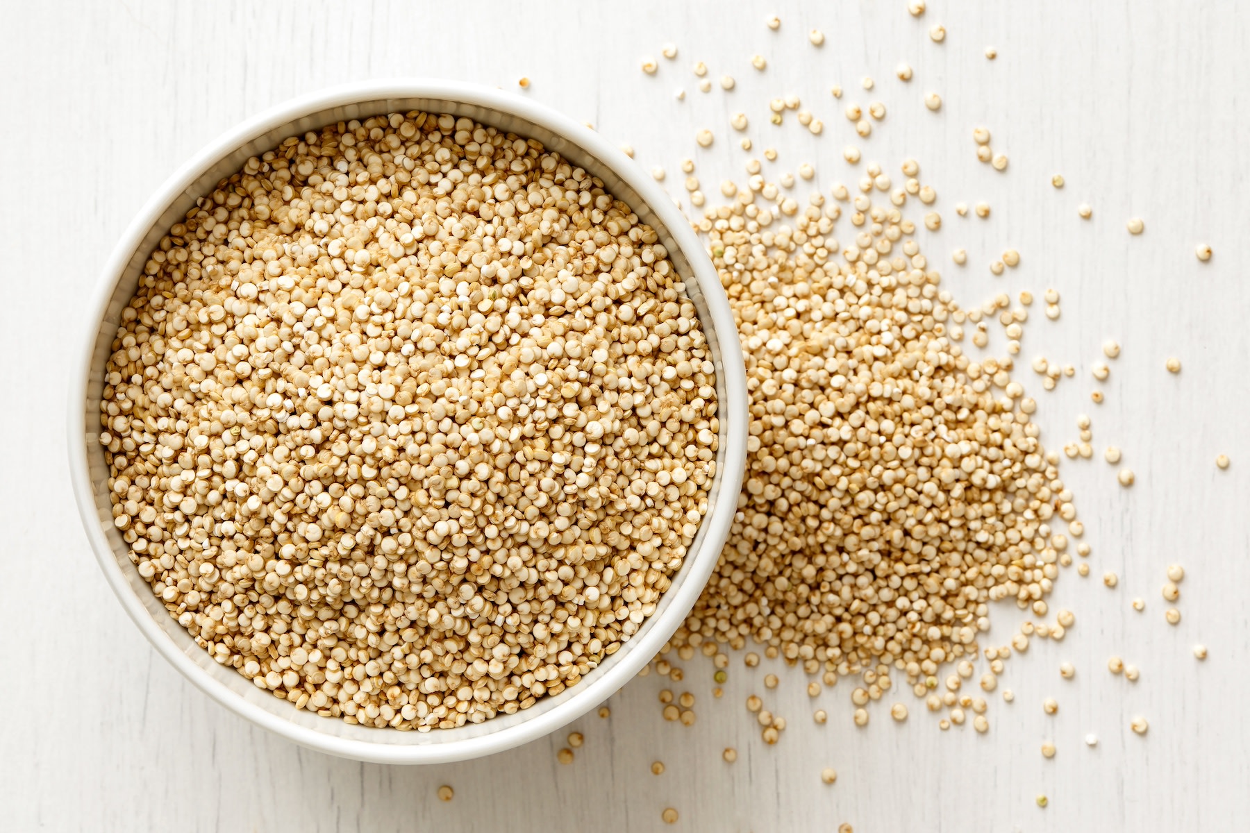 A bowl of quinoa seeds against a white background.