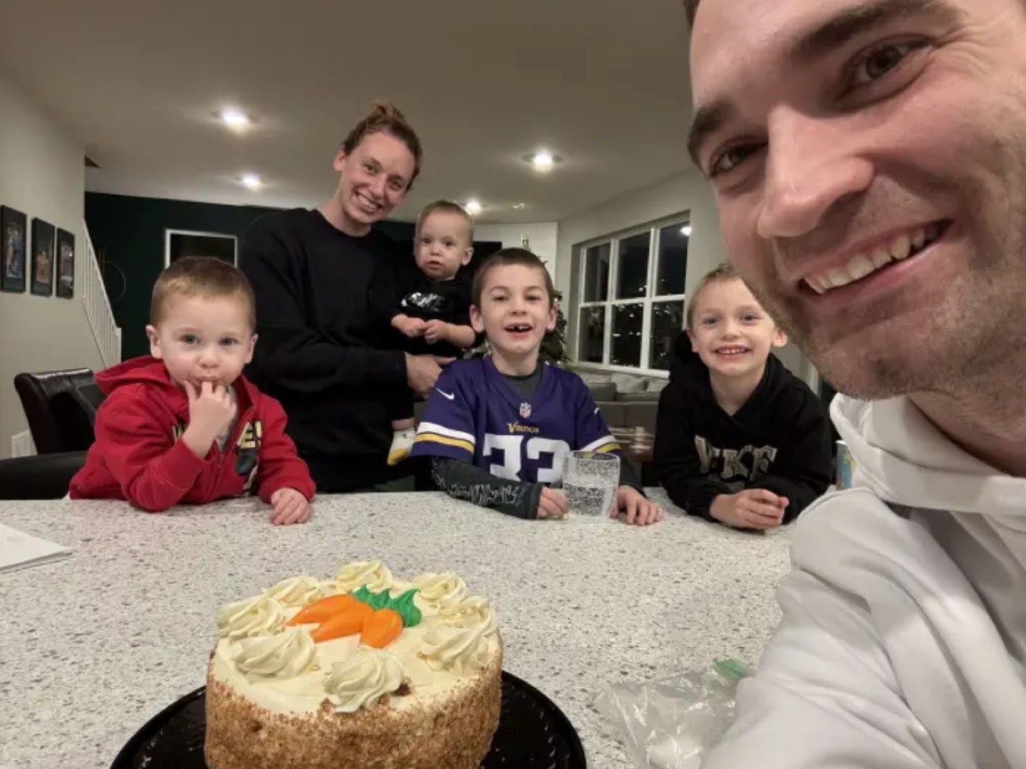 A Peloton Member smiling family in the background and a cake in the foreground