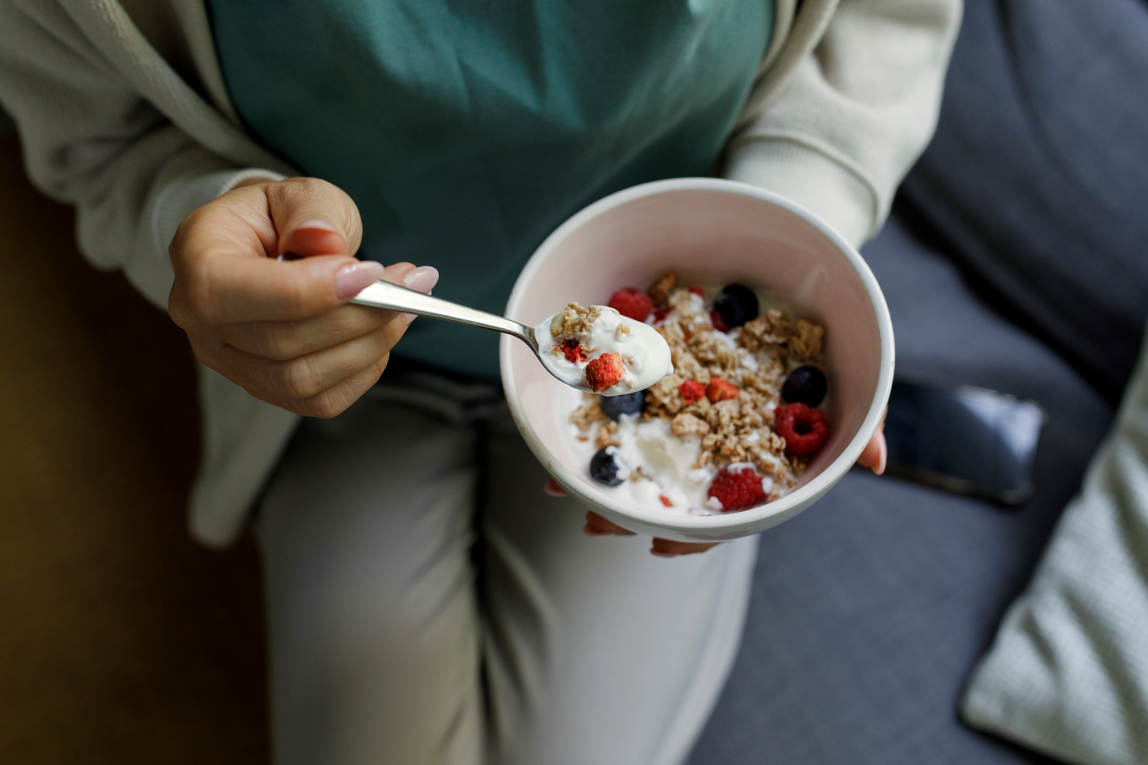 A person eating a Greek yogurt parfait as a healthy late-night snack,