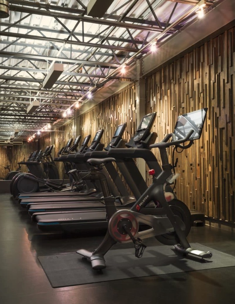 A Peloton Bike in a gym next to other cardio equipment