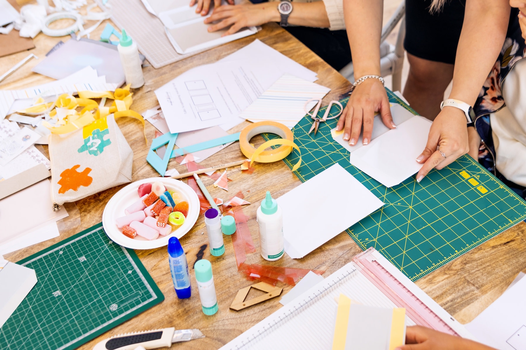 A group of friends making vision boards with arts and crafts supplies like colorful paper and glue.