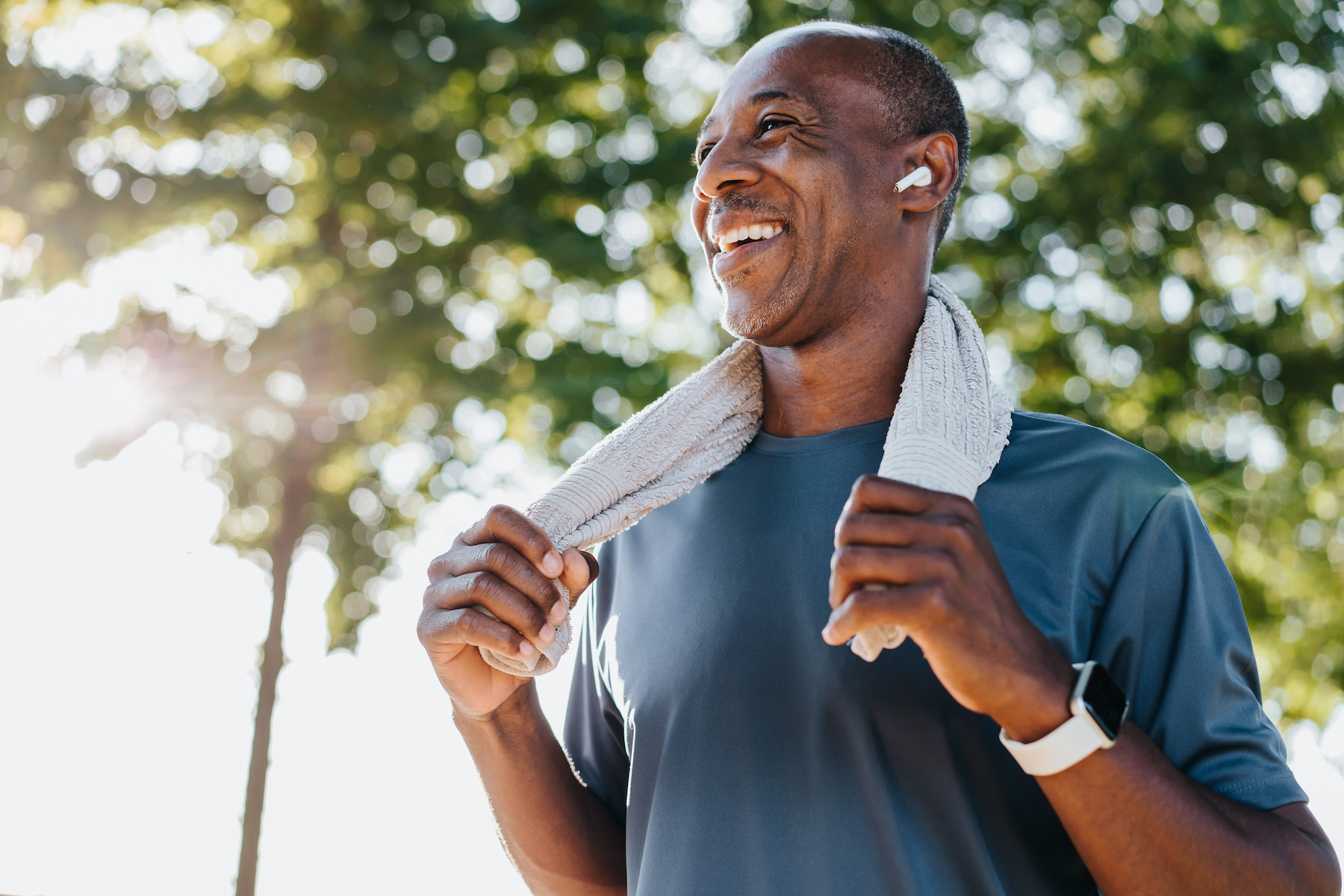 A man smiling after a workout while holding a sweat towel around his neck. Learn how to get more energy in this article.