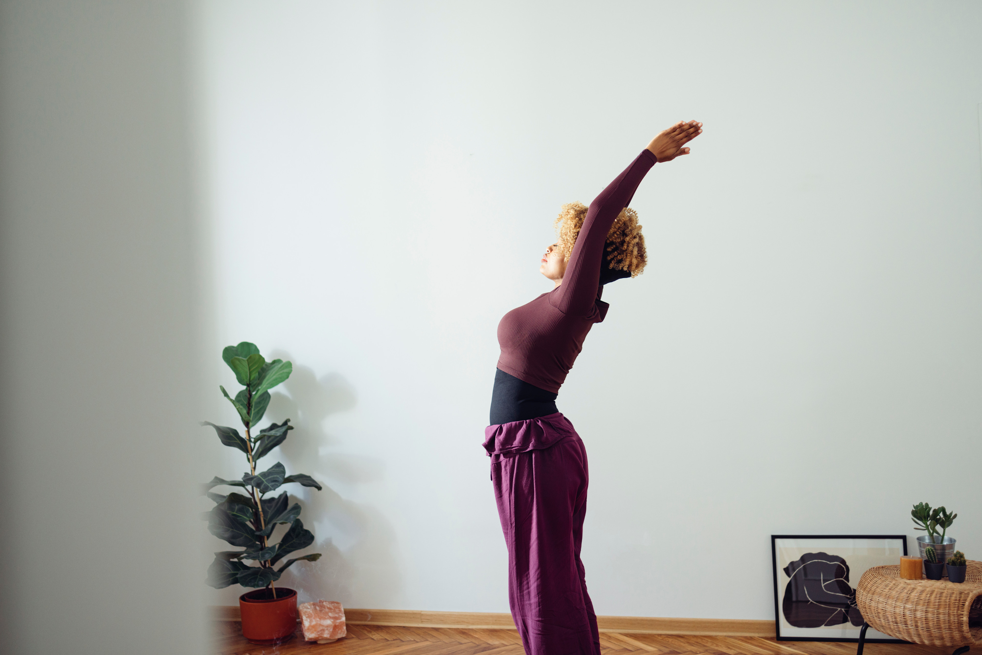 Woman does morning stretches in bright morning light at home
