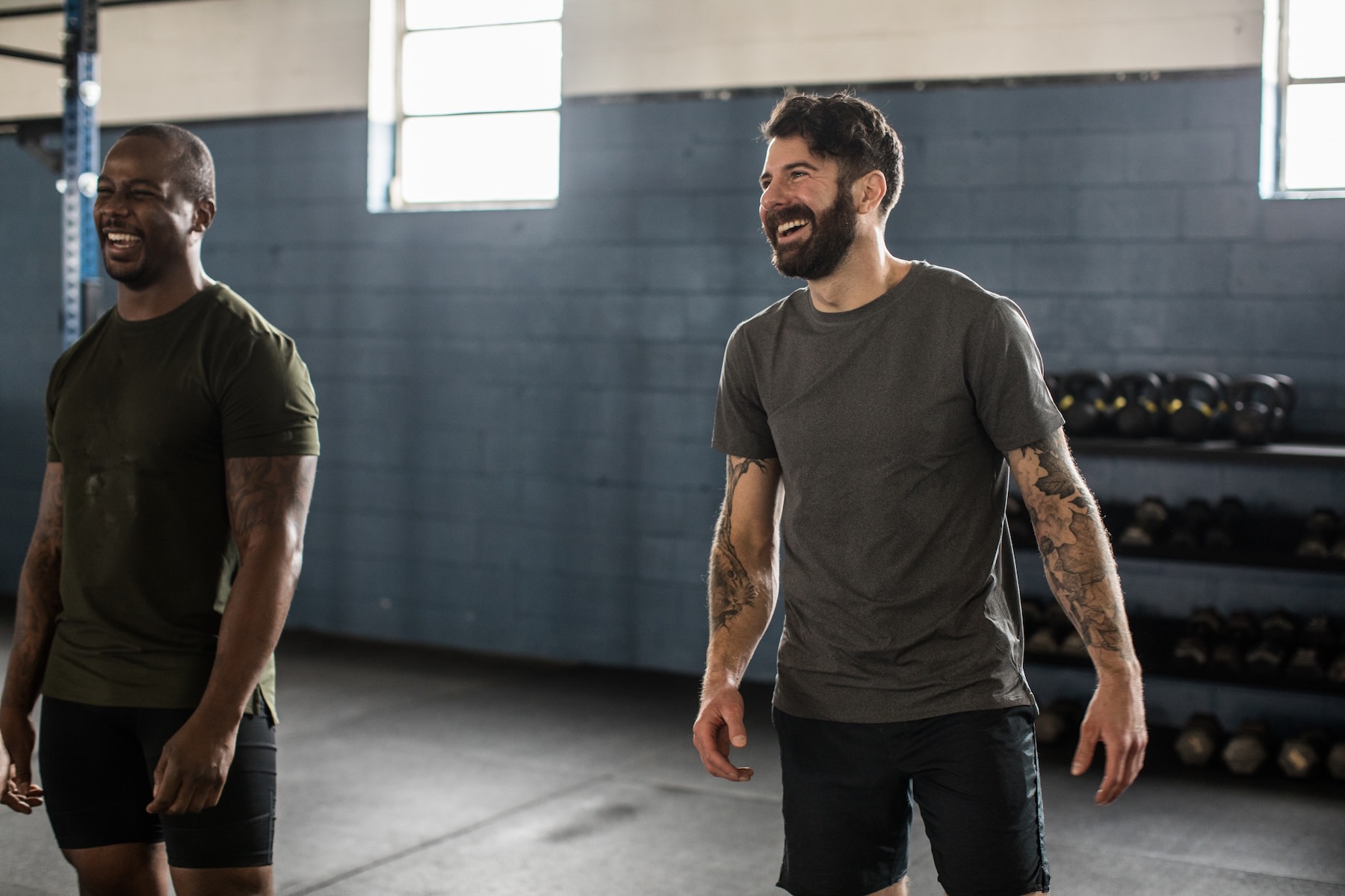 Two men laughing together at the gym. They feel good after lifting weights.