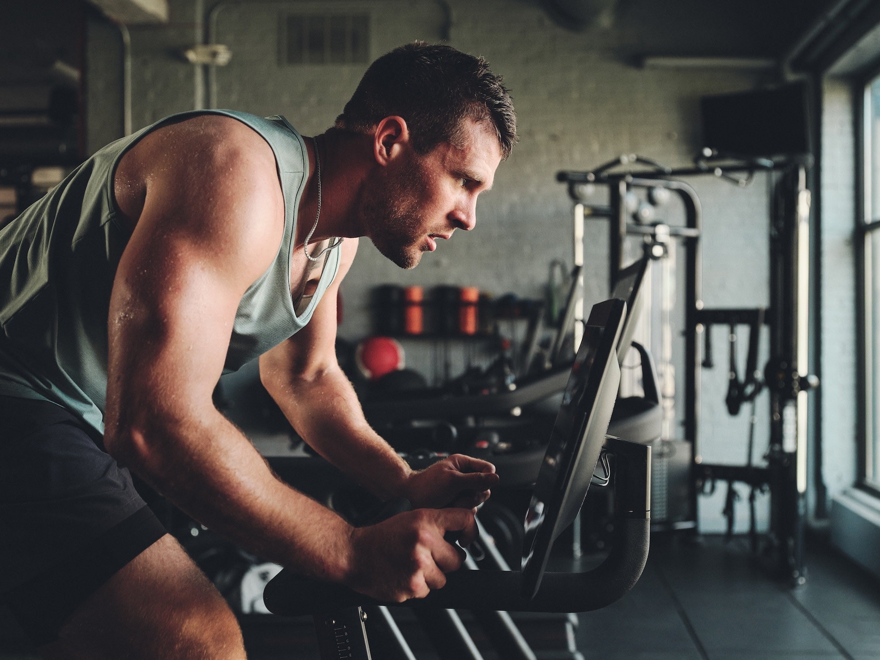 TJ Watt exercising on a Peloton Bike in a gym facility.