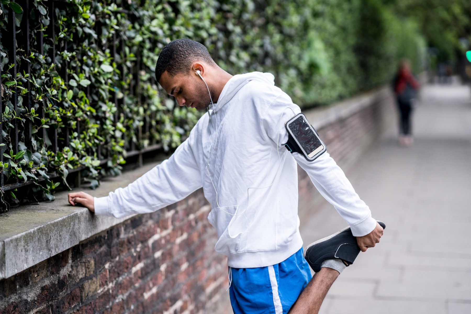 Man does an it band stretch before heading out on a run