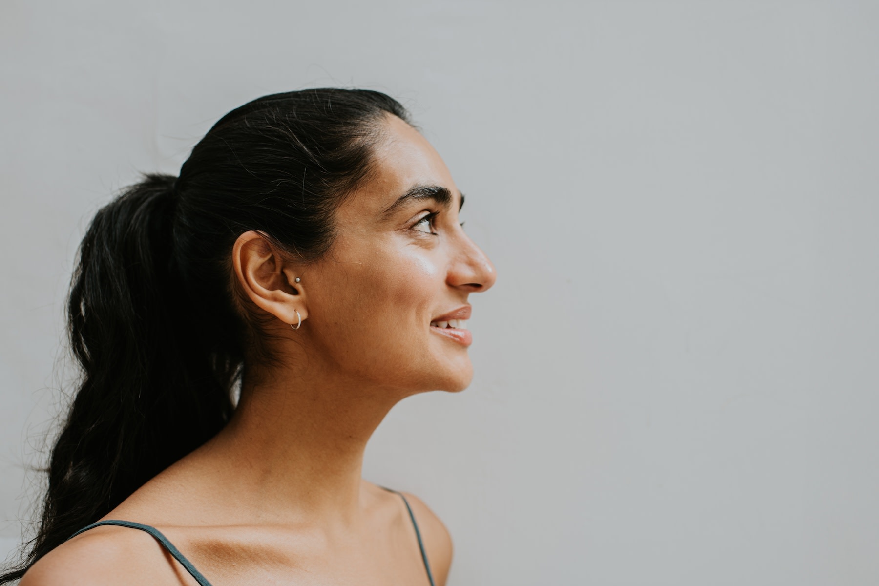 A side profile of a young woman smiling and looking up.
