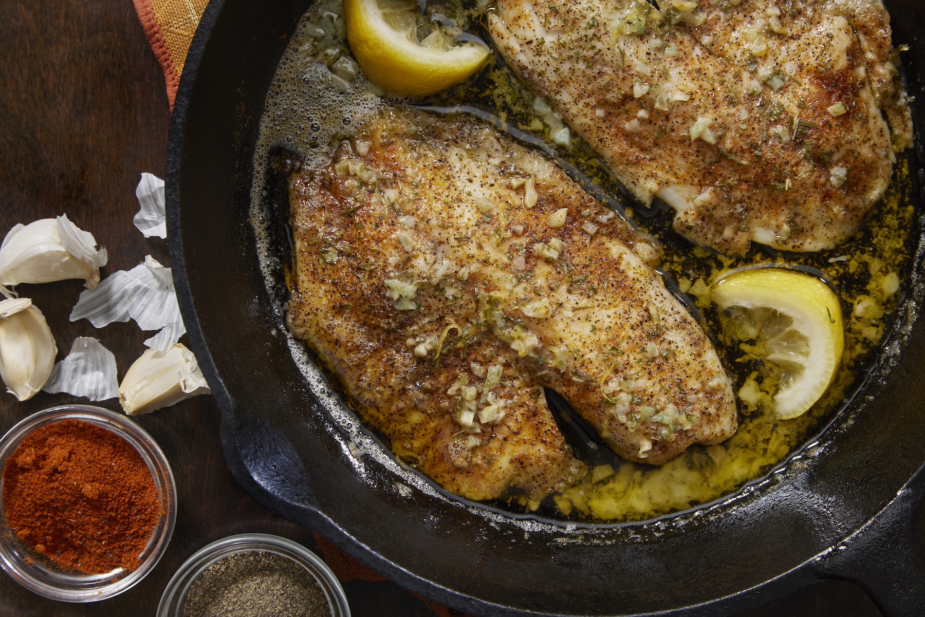 Baked tilapia (a lean protein) in a garlic butter sauce in a pan.