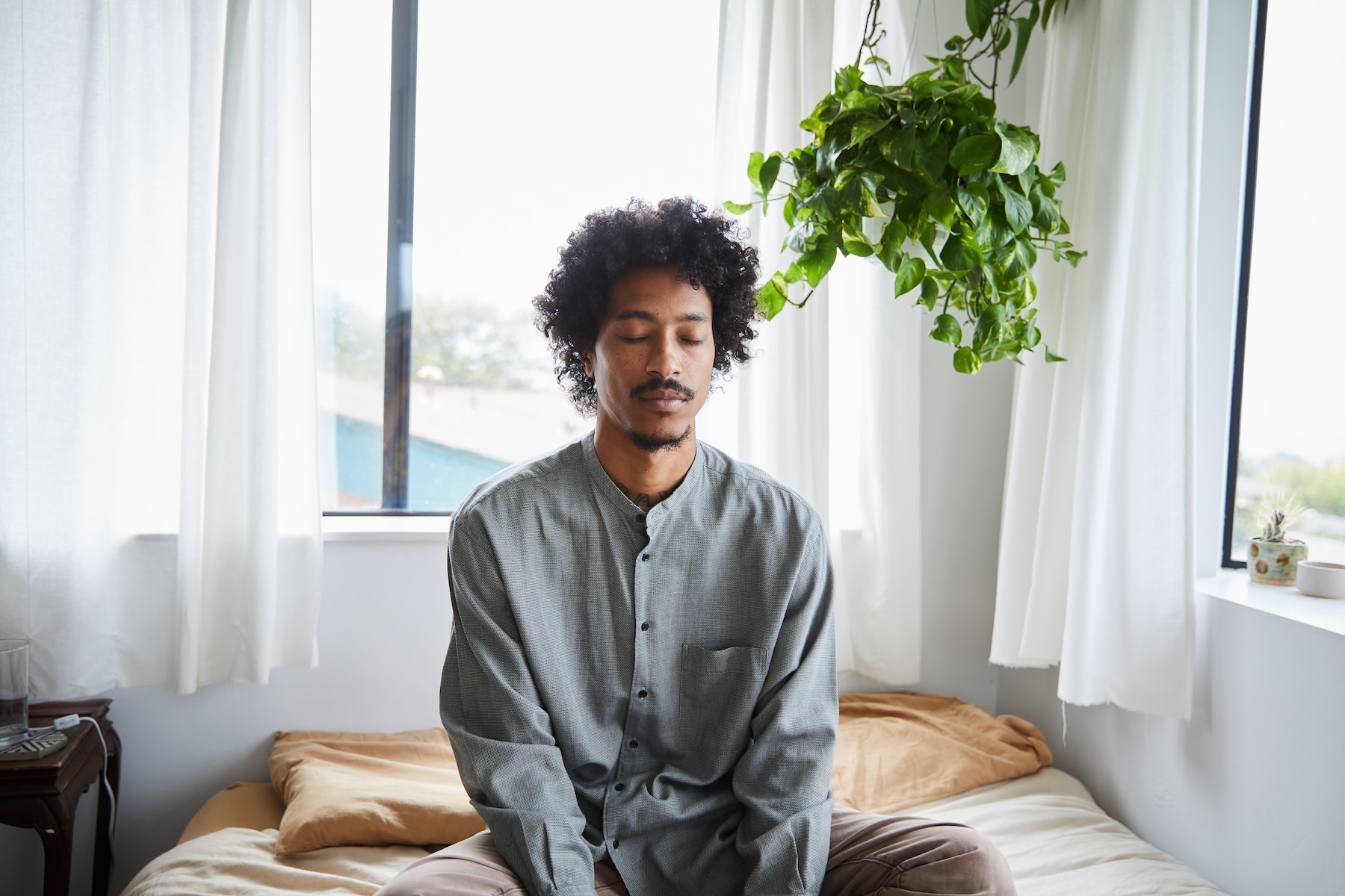 A man meditating at home in a sunny room as part of his habit loop.