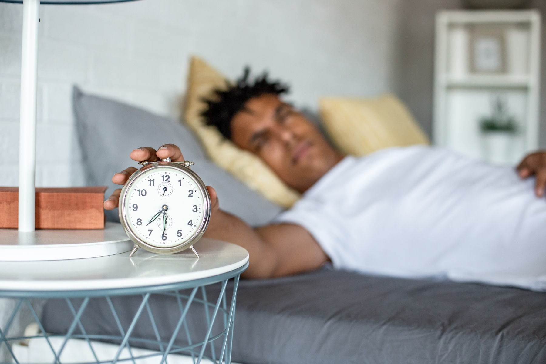 A man snoozing his alarm clock.