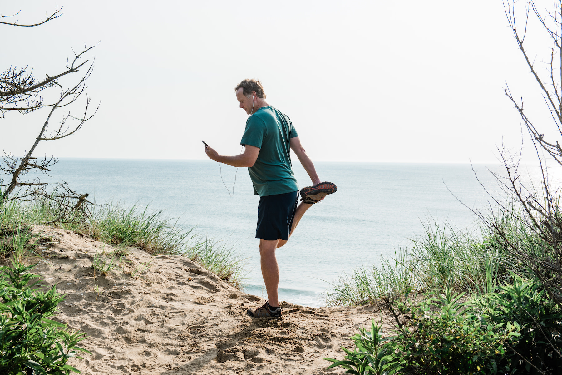 Man looks at phone while exercising outdoors