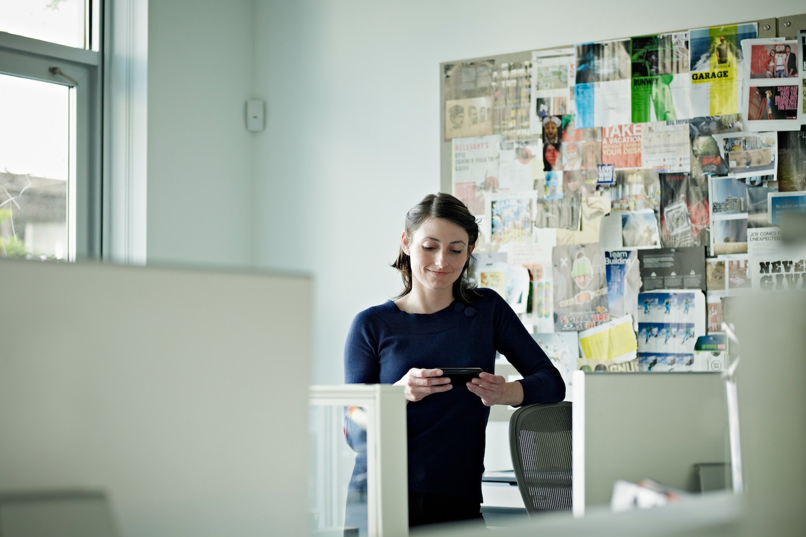 A woman standing in front of a vision board in her office.