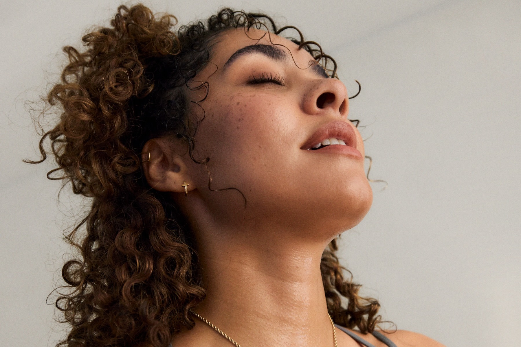 A woman practicing breathwork. She's breathing deeply through her mouth and closing her eyes.
