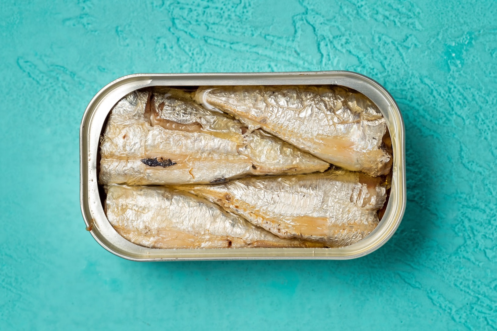 A tin of sardines (a high-protein snack) on a teal background.