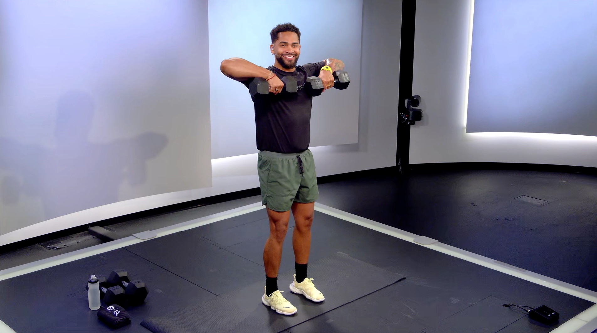 Peloton instructor Rad Lopez demonstrating a dumbbell upright row with proper form