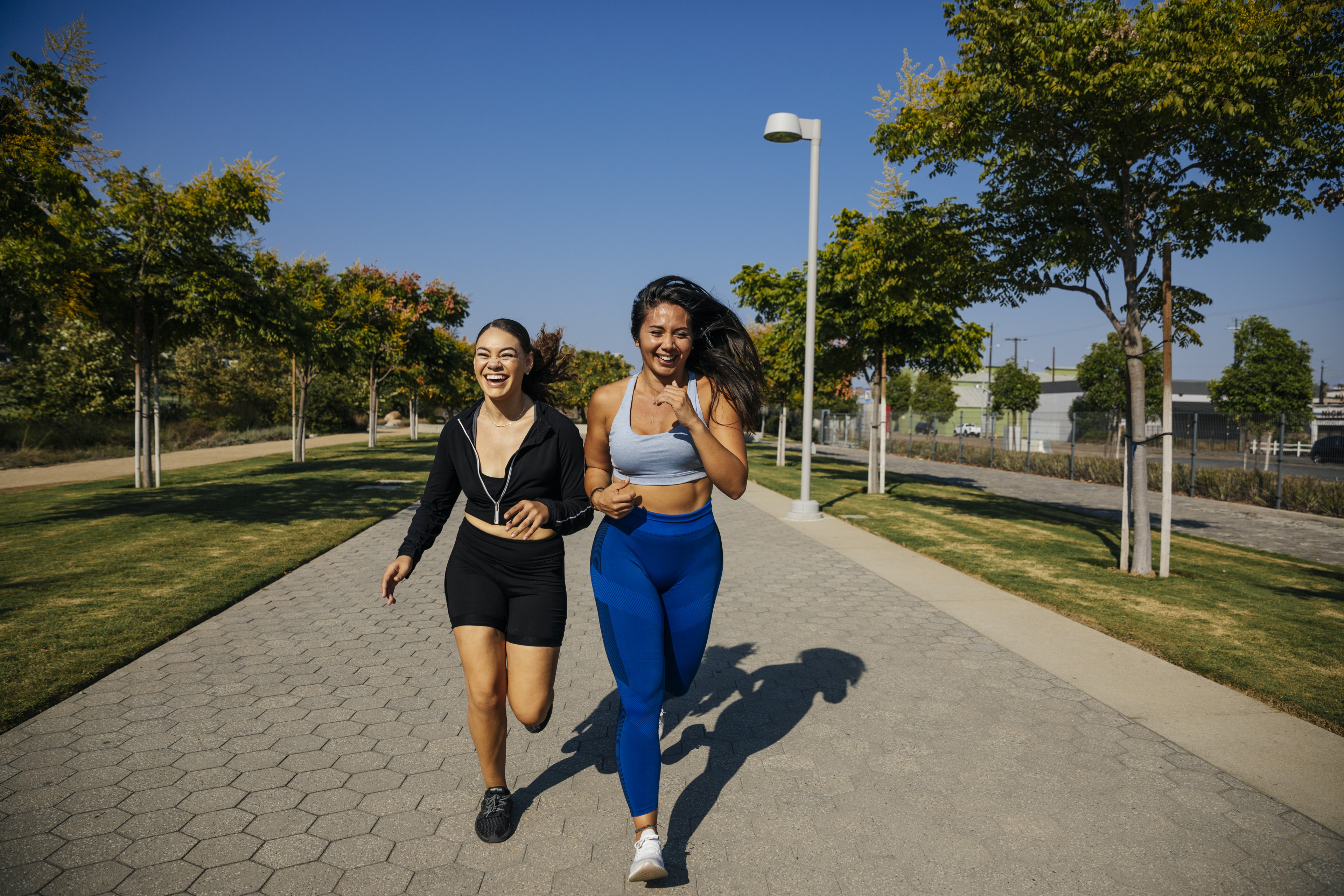 Two friends run outdoors together, a form of aerobic exercise