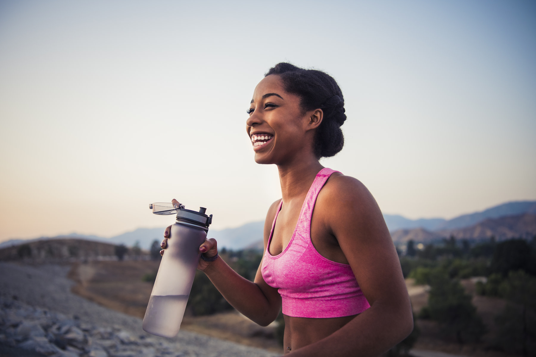 Woman drinks from a water bottle while on a run
