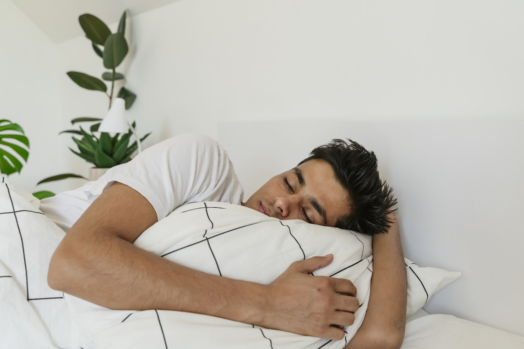 A man sleeping in bed in a bright, sunny room.