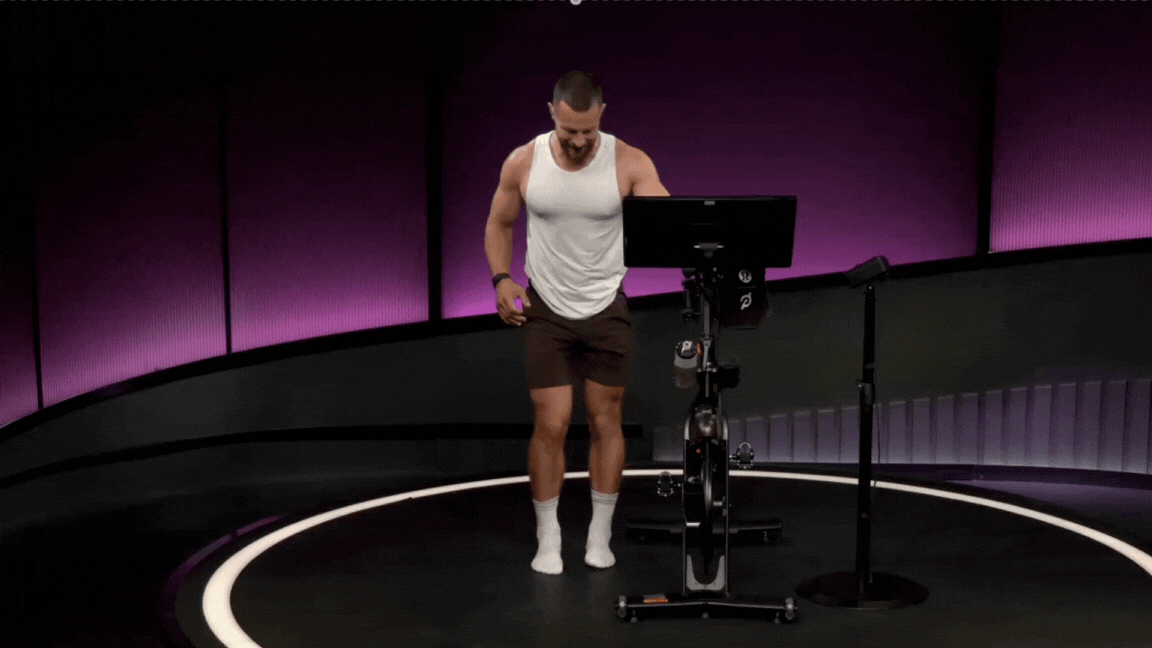 Peloton instructor Erik Jäger demonstrates a standing figure four stretch during a Peloton stretch class.