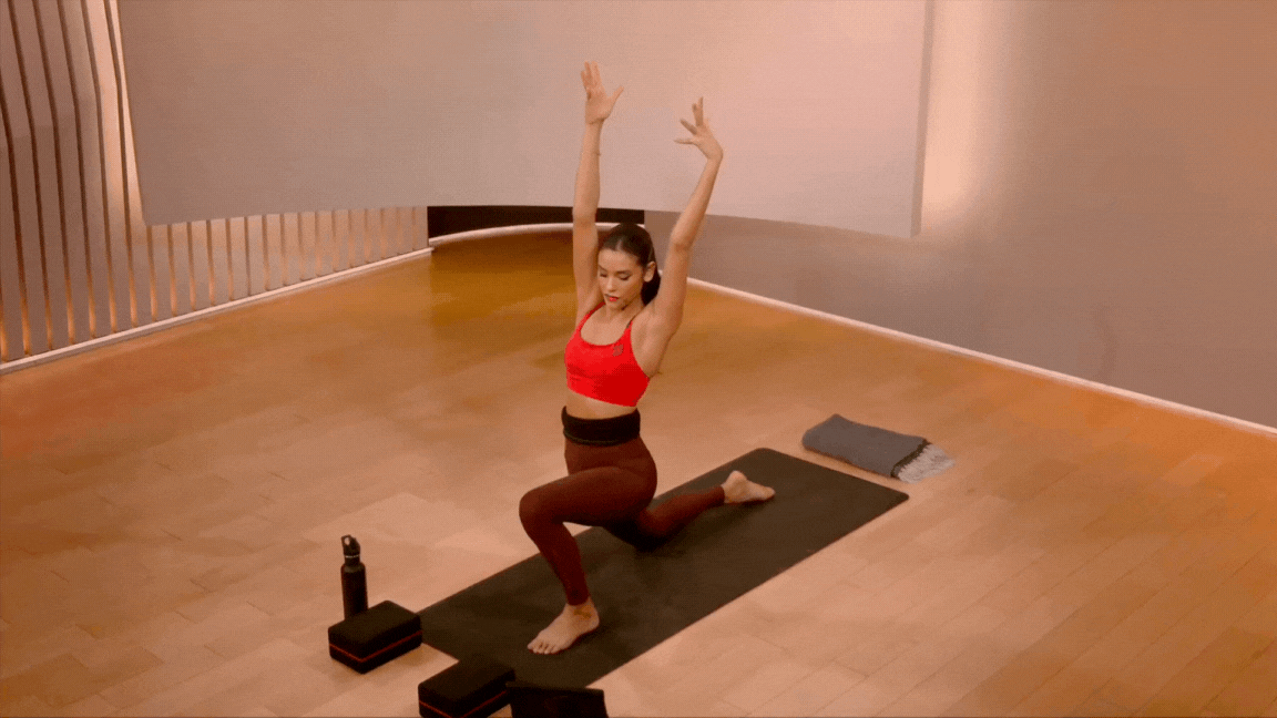 Peloton instructor Aditi Shah demonstrates a low lunge with side bend stretch