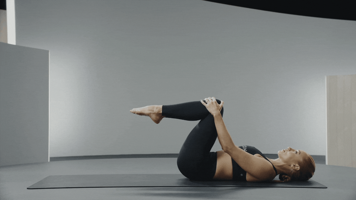 Jess King demonstrates a single leg stretch, a beginner Pilates exercise 