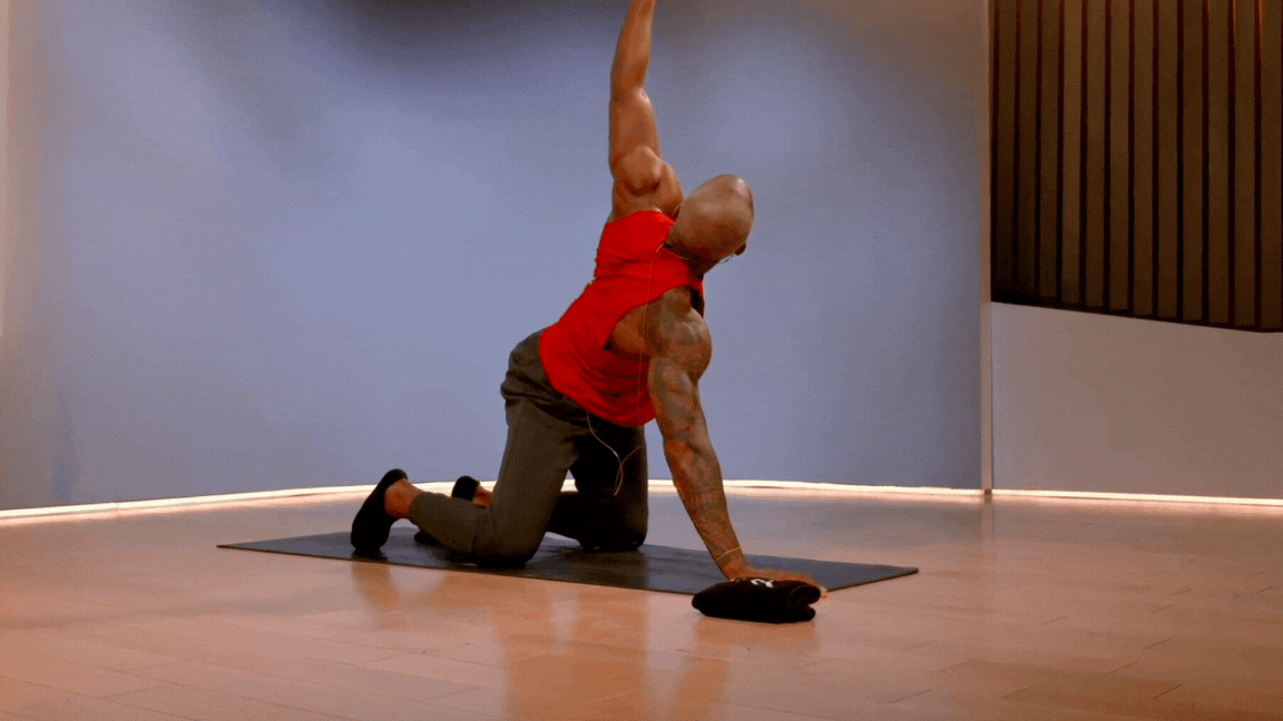 Peloton instructor Adrian Williams demonstrates a dynamic thread the needle stretch in a mobility class