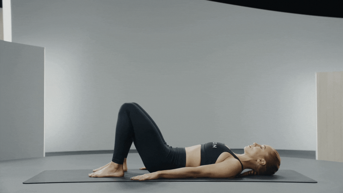 Peloton instructor Jess King demonstrating Pilates breathing in a pelvic curl or articulating bridge