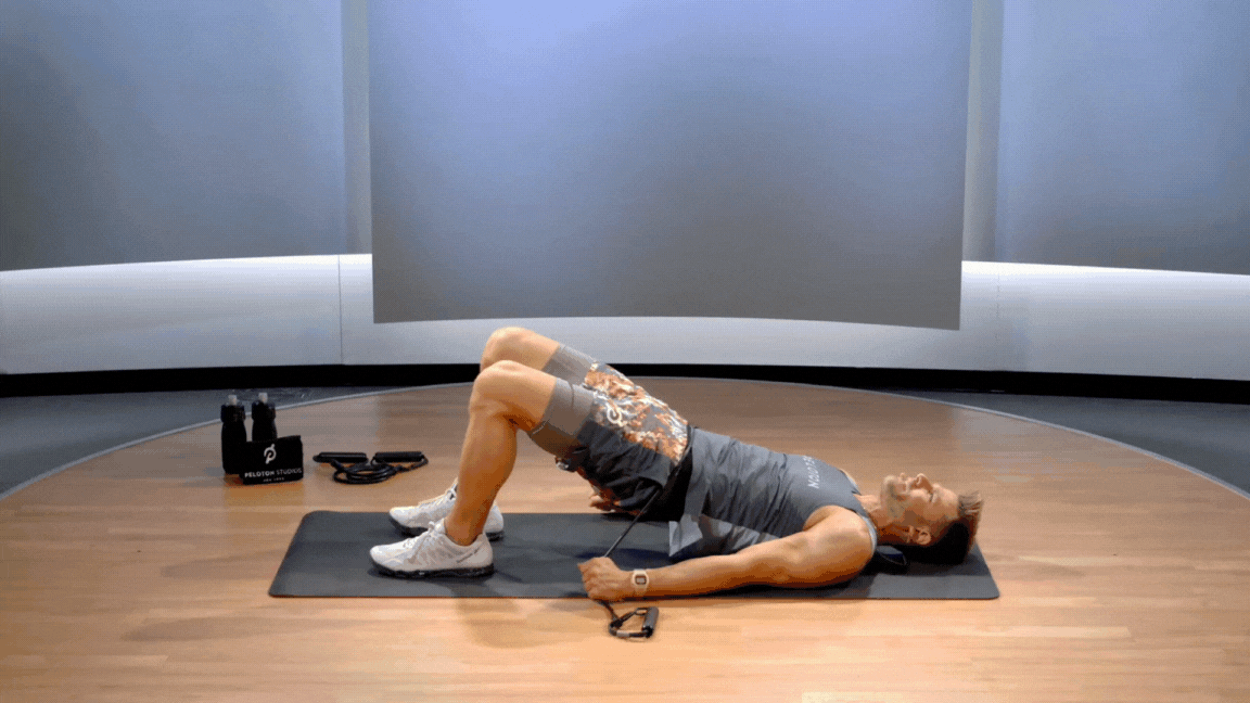 Peloton instructor Andy Speer demonstrates a resistance band glute bridge.