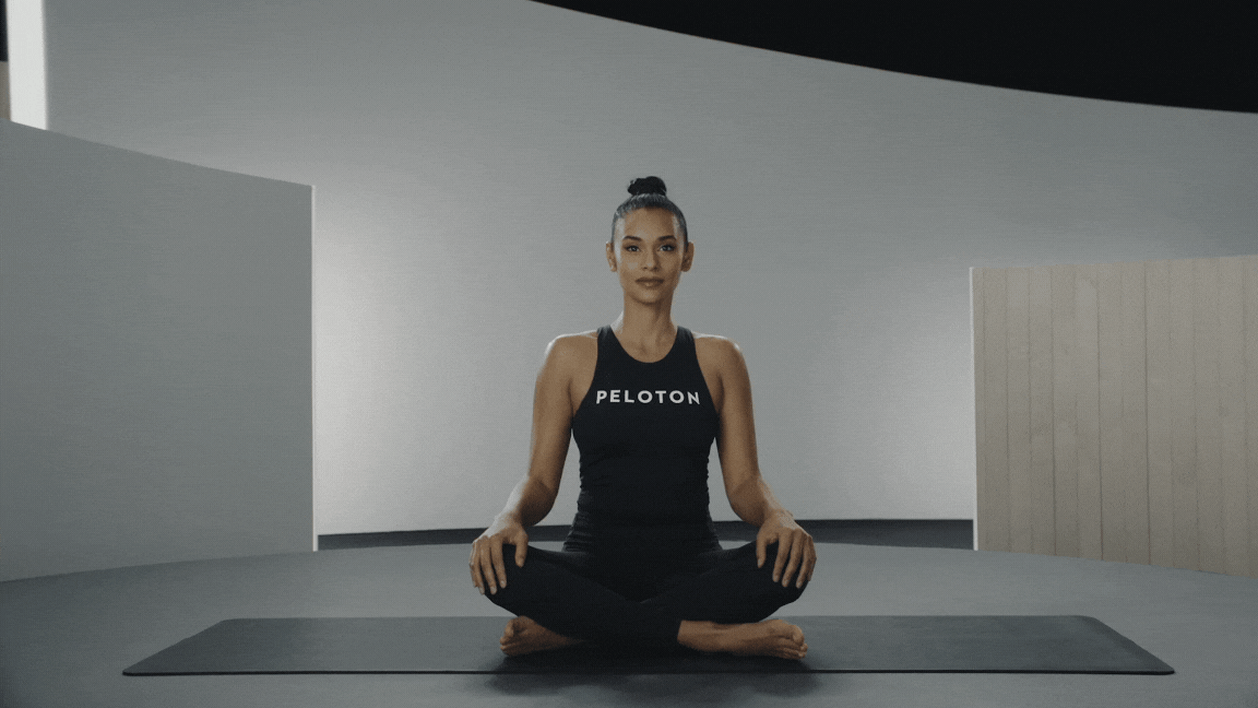 Peloton instructor Aditi Shah demonstrates a seated yoga twist 