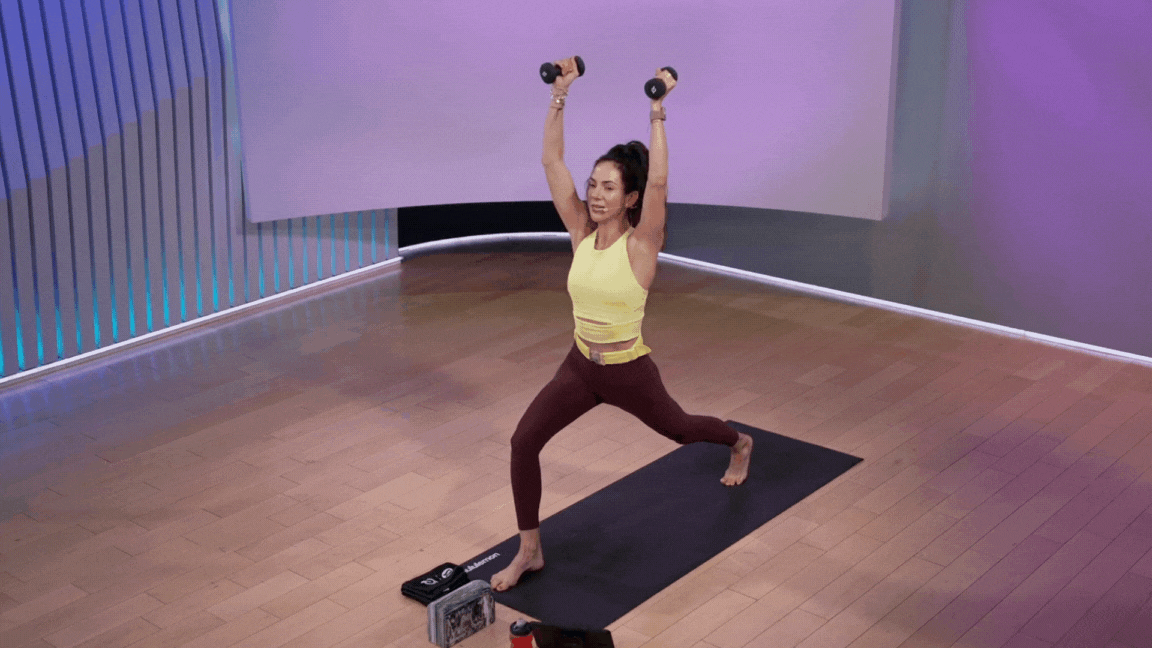 Peloton instructor Mariana Fernandez demonstrates a high lunge with weights during a yoga class with weights.
