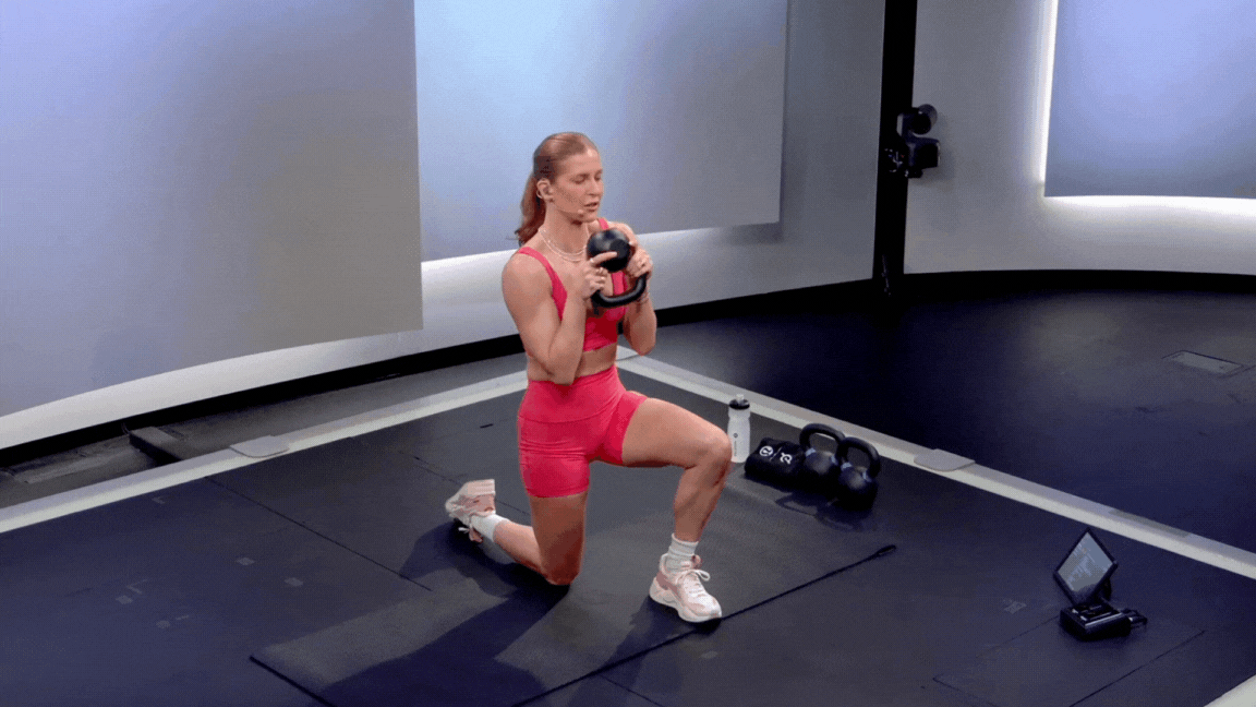 Peloton instructor Rebecca Kennedy demonstrates a kneeling kettlebell halo with a triceps extension during a Peloton kettlebell strength class.