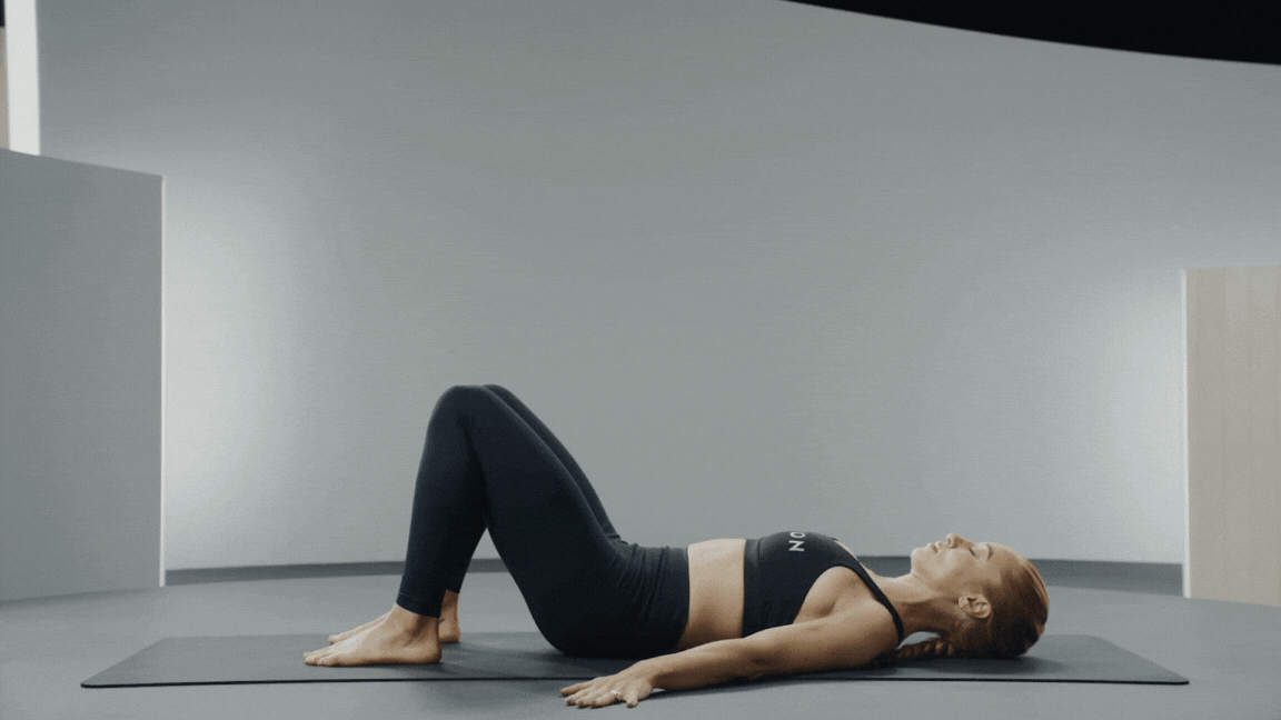 Peloton instructor Jess King demonstrates a lying pelvic tilt to show how to find a neutral spine during exercise.