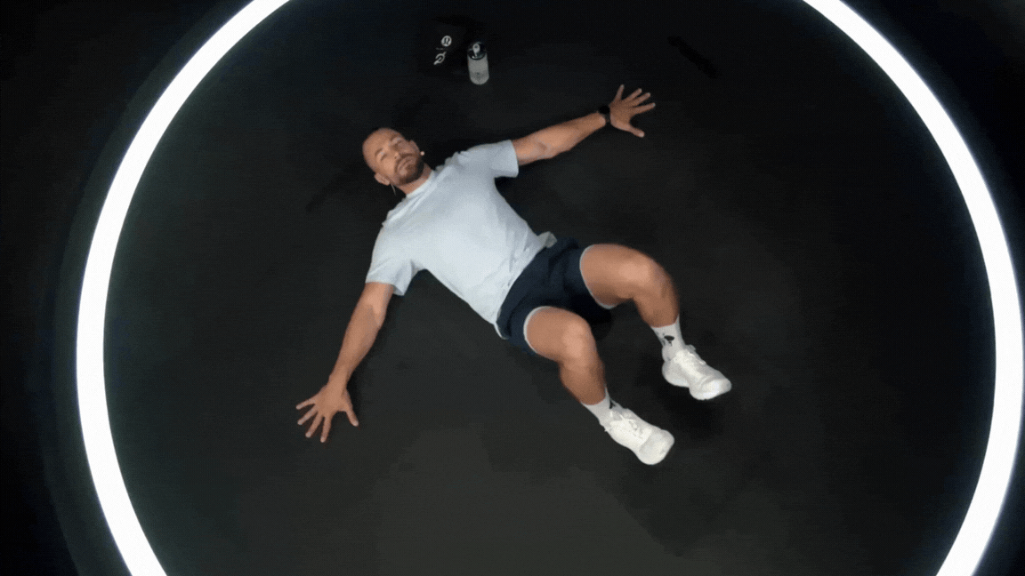 Peloton instructor Erik Jäger demonstrates windshield wiper knees spinal mobility exercise.