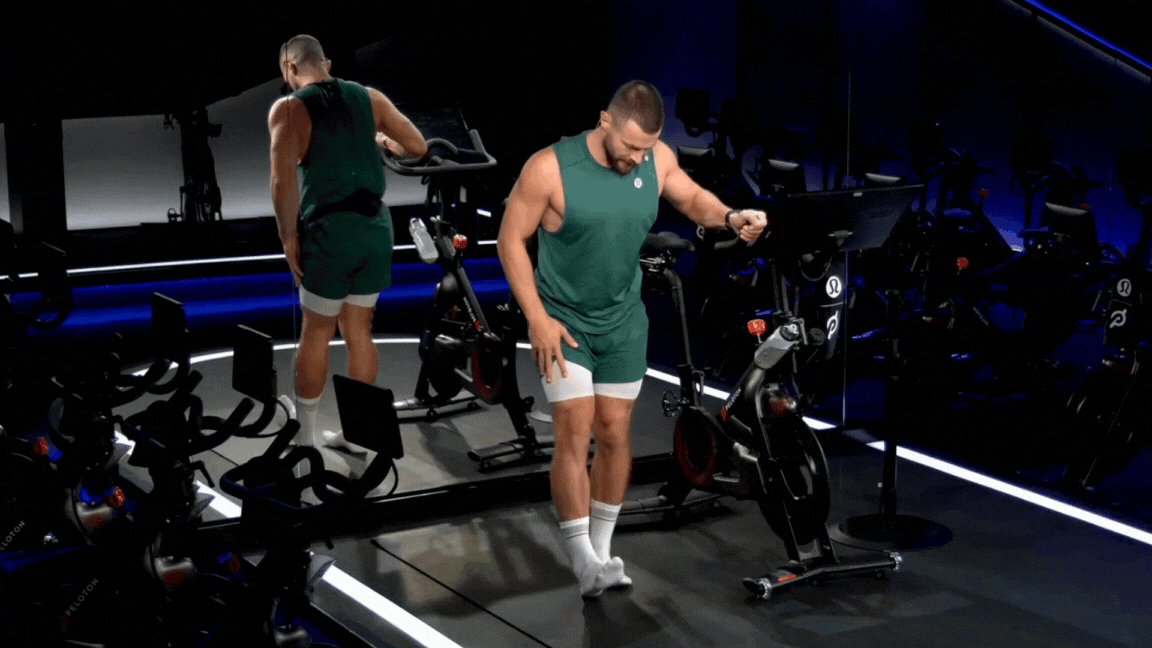 Peloton instructor Erik Jäger demonstrates a standing hamstring stretch during a Peloton stretch class.