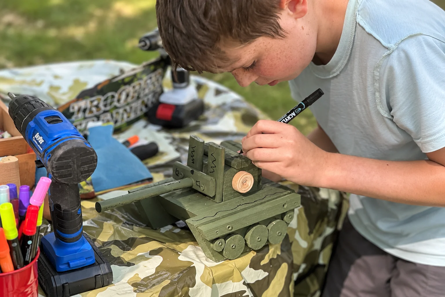Young Boy Painting a Wooden Tank.png