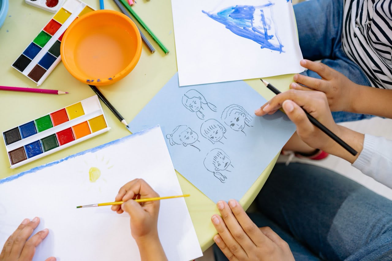 Young children's hands painting with watercolors
