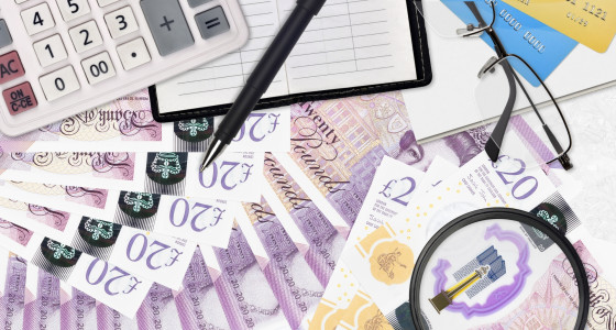 A magnifying glass over a spread of pound notes