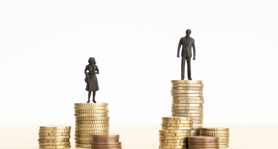 Two stacks of coins with a man standing on one and a woman standing on the other.