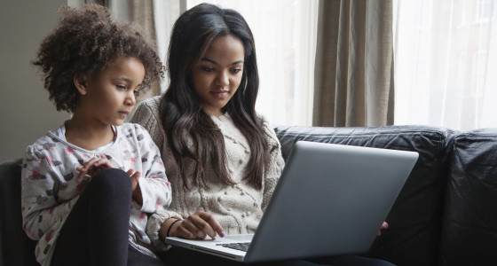 A toddler and an older chiid use a laptop together