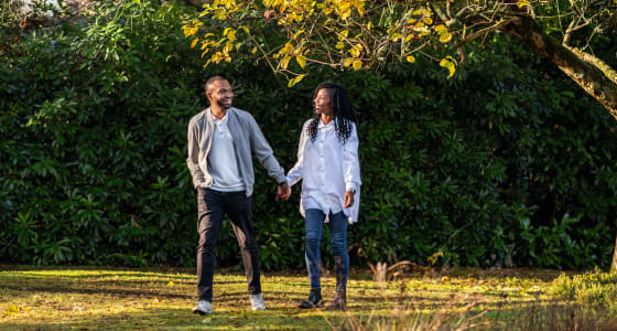 Ken and Mary Okoroafor walking outside in a park surrounded by trees and grass