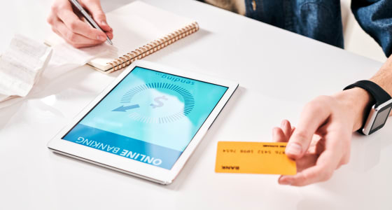 Woman holds bank card while doing online banking on a tablet computer