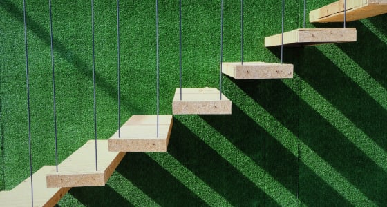 7 wooden steps suspended in front of a green astroturf background